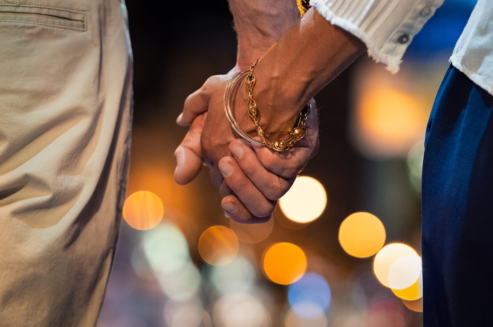 A close up of a couple holding hands against the city lights. Learn more about infidelity counseling in Roseville, CA and other services by searching infidelity therapist near me today. An infidelity counselor in Roseville, CA can offer support today