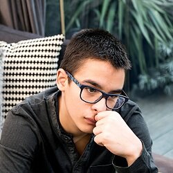 Upset teen boy in a hoodie and black glasses representing how working with a teen therapist for teen counseling can help. Get support from the relationship therapy center