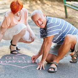 A middle aged couple drawing a heart with the words “get married” in chalk representing a couple entering a second marriage. Before you remarry, seek premarital counseling in Fair Oaks, CA