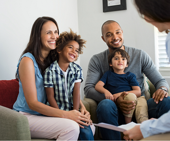 Happy family sits on a couch next to a professional individual. This represents the joy that can be felt from getting family therapy in Fair Oaks, CA and family therapy in Roseville, CA with a family therapist at the Relationship Therapy Center