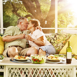 Photo of a couple kissing while eating a picnic on a sunporch representing how spending relaxing time together can help married couples put the spark back into a marriage.