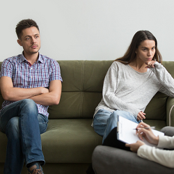 A young couple on opposite sides of a couch who look unhappy. They represent a couple who is attending discernment counseling with a marriage counselor in Roseville, CA. Our couples therapists can also offer online therapy in California.