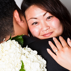 Photo of an Asian woman hugging a man representing a young couple who are married and seeing a California couples therapist to help strengthen their relationship.