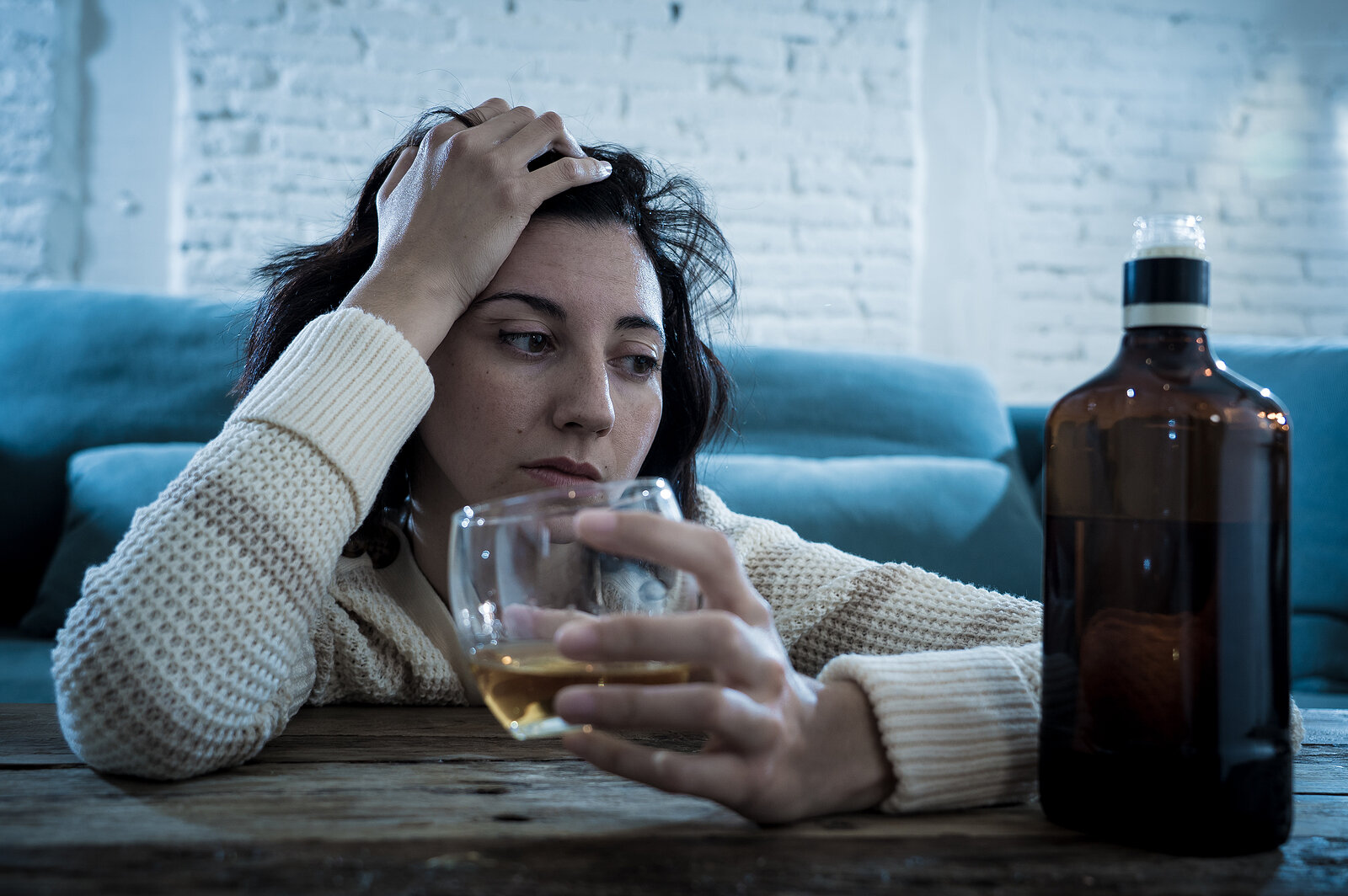woman holds a glass of wine looking distressed. She gets addiction therapy in California at The Relationship Therapy Center