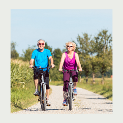 An older couple ride bikes next to one another on a sunny day. A marriage counselor in California can offer support for mature marriages. Learn more about online marriage counseling in California, a couples retreat in California, and more.