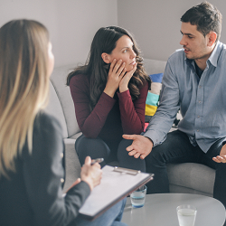 A couple appear to argue with one another as a a therapist listens. This could represent a marriage counselor in California meeting with a couple. Learn more how online marriage counseling in California can offer support. 95678