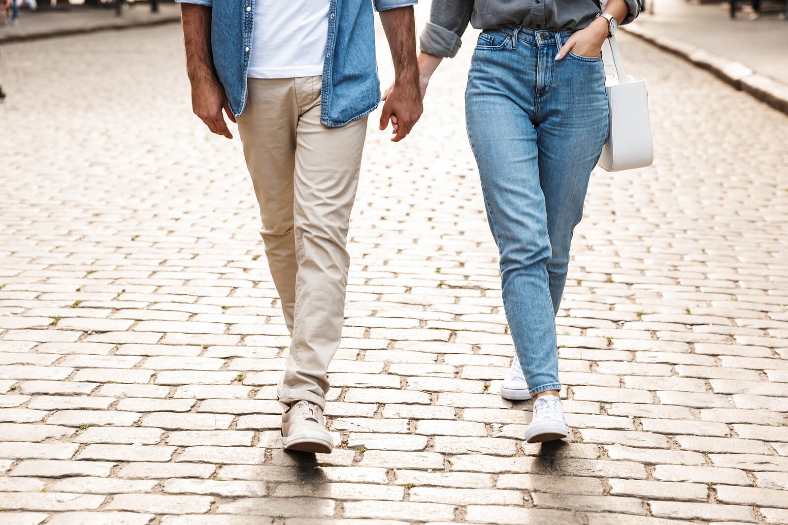 A close up of a couple holding hands as they walk down a brick road. A marriage counselor in California can help cultivate a deeper connection. Learn more about a marriage counseling retreat in California or online marriage counseling in California.