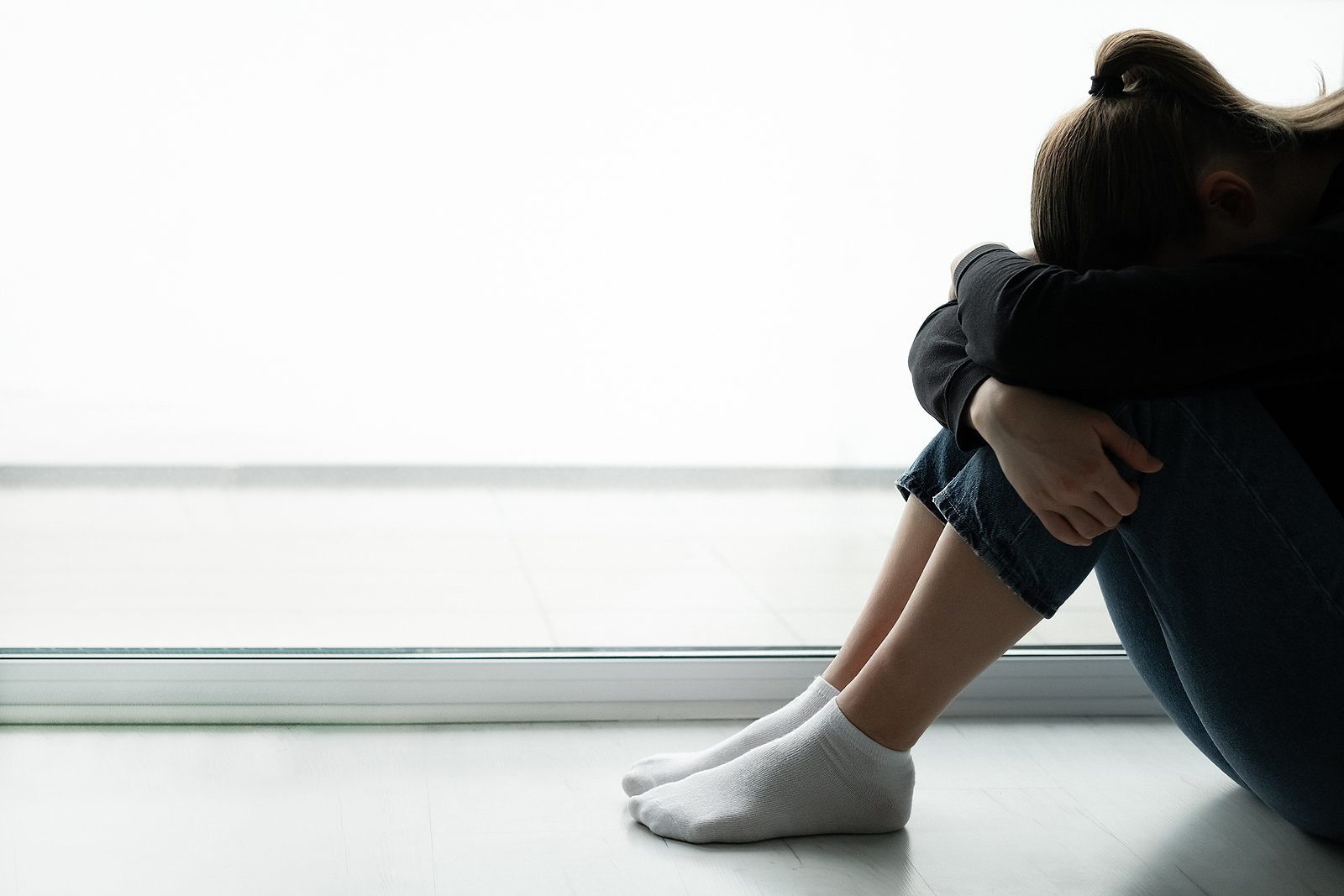 A teen sits alone near a window while hiding their face and hugging their legs. Learn how a therapist for teens in Roseville, CA can tell you more about teen therapy in Fair Oaks, CA, and other services. Search for teen therapy Sacramento for support