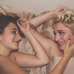 Two women smile as they lay in bed next to one another. This shows the intimacy cultivated by sex therapy in Sacramento, CA. Learn more about counseling in Roseville, CA and other services by contacting a therapist in Fair Oaks, CA today.
