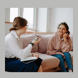 A teen smiles as they talk with a therapist. This could represent getting to know a therapist in Fair Oaks, CA. Our team offers depression treatment in Roseville, CA, and other services including trauma therapy in Roseville, CA. 95678