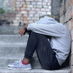 A teen sits on a step while hiding their face. This could represent the isolation that a therapist for teens in Roseville, CA can address. Learn more about depression treatment in Roseville, CA and other services like teen therapy in Roseville, CA.
