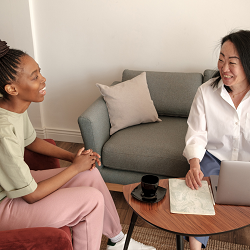 A person with paper and a laptop smiles at a client sitting near them. This could represent a therapist for teens in Roseville, CA helping a client. Learn more about teen therapy in Roseville, CA and other services like depression treatment.