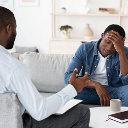A man holds his head with an upset expression as their therapist gestures across from them. This could represent meeting with an anxiety therapist in Fair Oaks, CA. Learn more how anxiety treatment in Roseville, CA can support you in finding peace! 9