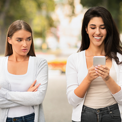 A woman gives a harsh look to their friend while they are looking at their phone. This could represent the mistrust that infidelity counseling in Roseville, CA can address. Contact an infidelity counselor in Roseville, CA to learn more.
