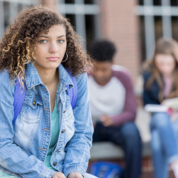 A teen looks blankly at the camera as their friends read behind them. A therapist for teens in Roseville, CA can help your teen deal with depression. Learn more about teen therapy in Roseville, CA and other services including depression treatment.